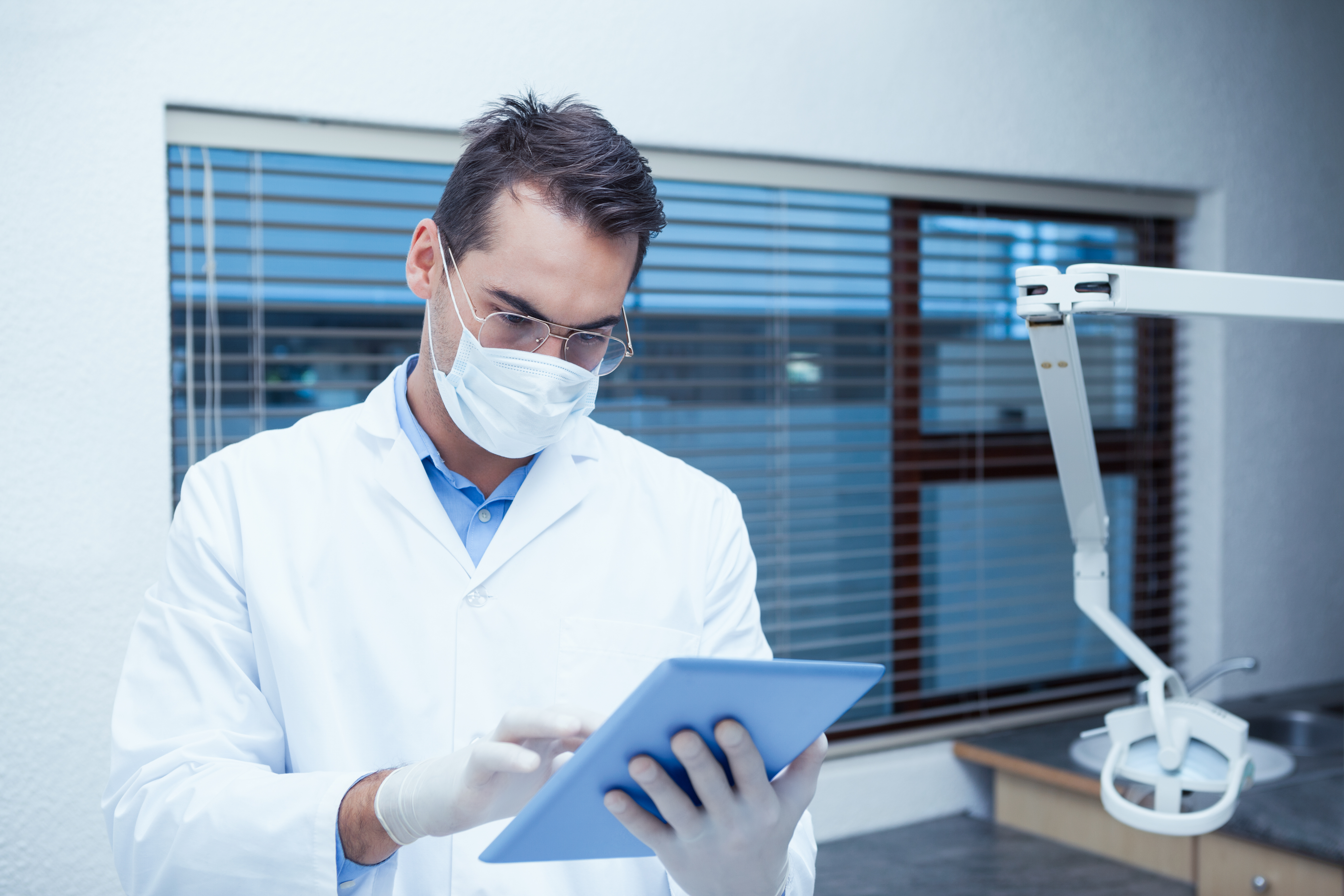 Oral surgeon reviewing patient record on tablet